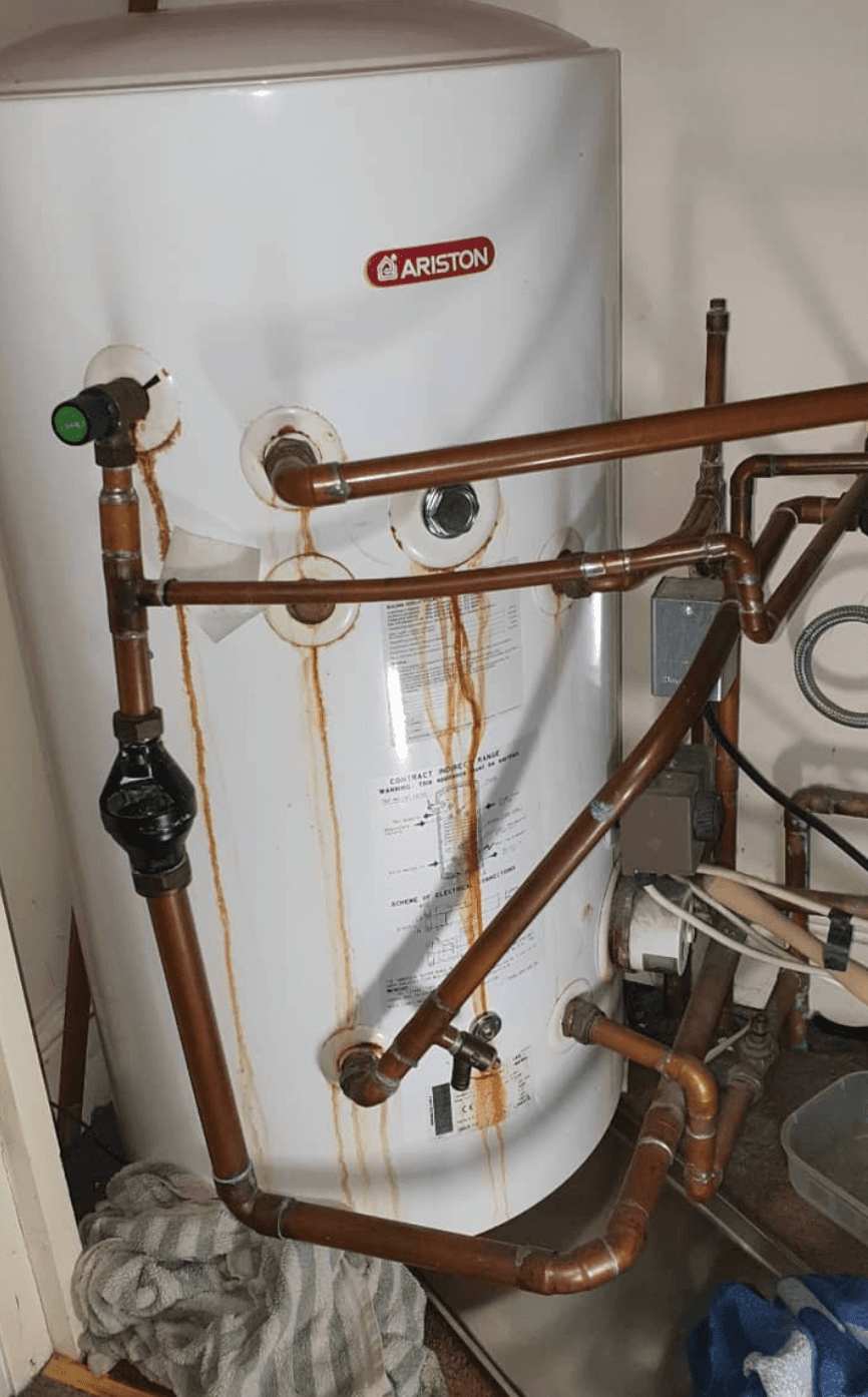 Older Ariston hot-water cylinder with messy copper pipework wrapped around the front before replacement