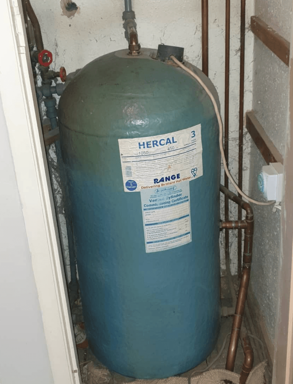 Old green Hercal hot-water cylinder in an airing cupboard before replacement